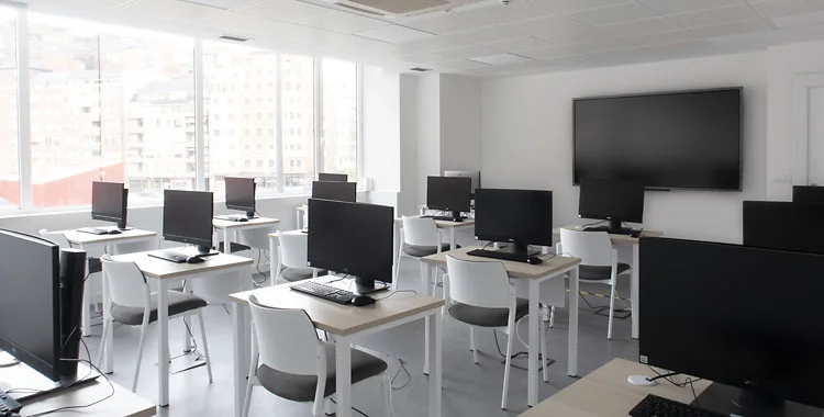 Aula espaciosa con equipos informáticos All-in-One.